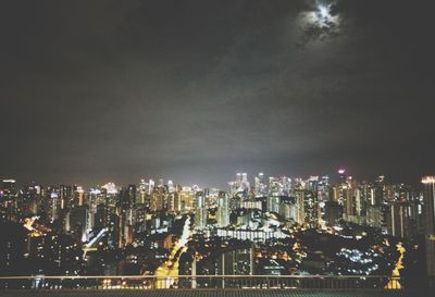 Illuminated buildings in city against sky at night