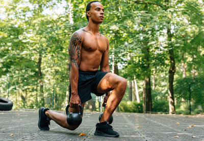 Full length of shirtless man sitting in garden