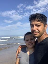 Portrait of smiling man on beach against sky
