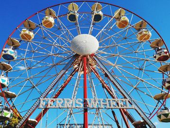 Low angle view of ferris wheel against blue sky