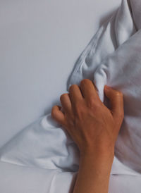 Low section of woman with hands on bed at home