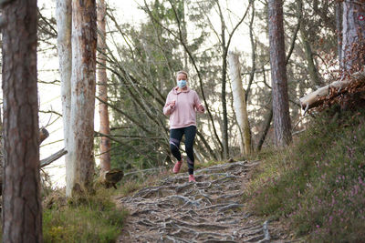 Full length of man running on road amidst trees in forest