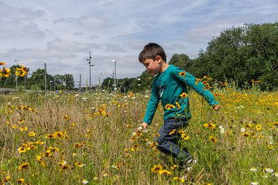 Full length of boy running on grassy field against sky