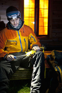 Man sharpening his crampons in front of camping pod in the uk