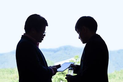 Side view of couple standing against sky