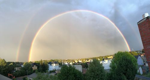 Rainbow over buildings in city against sky