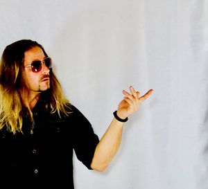 Woman wearing sunglasses standing against wall