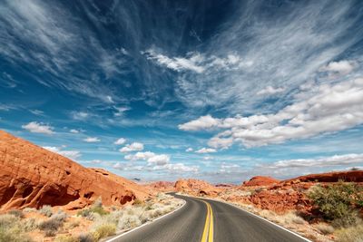 Empty road amidst landscape against sky