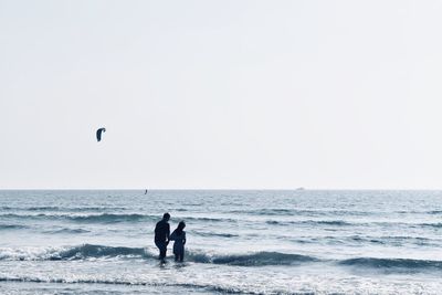 People on beach against clear sky