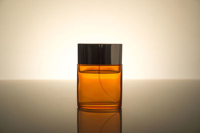 Close-up of perfume on table against beige background