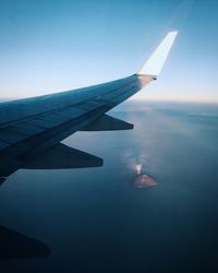 Close-up of airplane flying over sea against clear sky