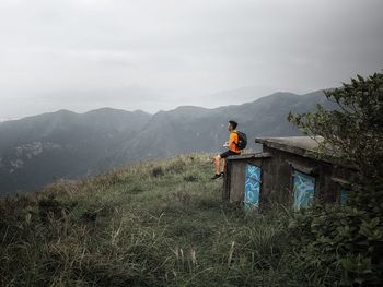 Rear view of man standing on mountain against sky