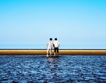 Man with umbrella on sea against clear sky