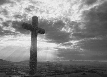 Low angle view of cross against cloudy sky