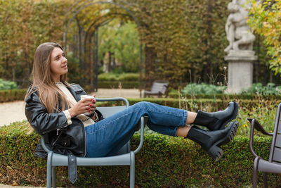 A beautiful woman is drinking hot tea and relaxing in a beautiful autumn park somewhere in europe.