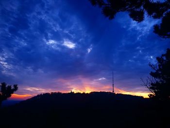 Silhouette landscape against dramatic sky during sunset