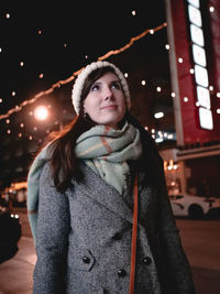 Young woman standing outdoors at night during winter