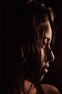 Close-up of young woman against black background