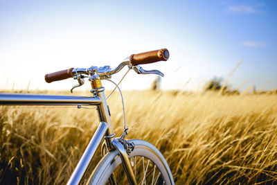 Bicycle on golden field against sky during sunset
