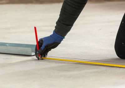 Low section of person taking measurements on floor at construction site