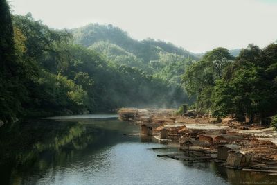 Bamboo shacks by river during foggy weather