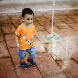 High angle view of cute boy standing on footpath