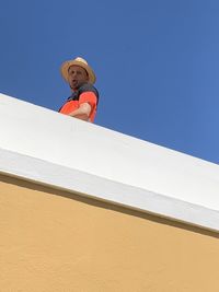 Low angle view of person against clear blue sky
