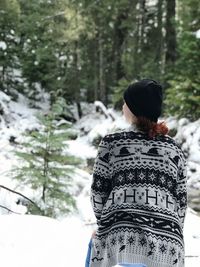 Rear view of woman standing in forest during winter