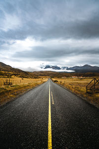 Diminishing perspective of empty road against cloudy sky