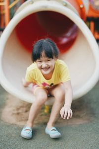 Full length portrait of smiling girl sitting in slide