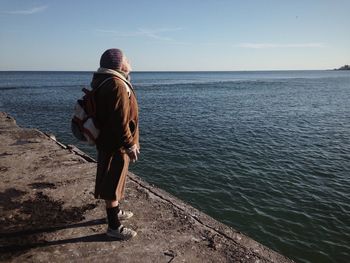 Woman standing on pier by sea against sky