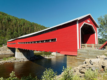 Red building by lake against clear blue sky