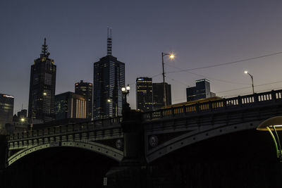 Illuminated modern buildings in city against sky at night