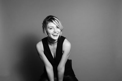 Portrait of smiling young woman against wall
