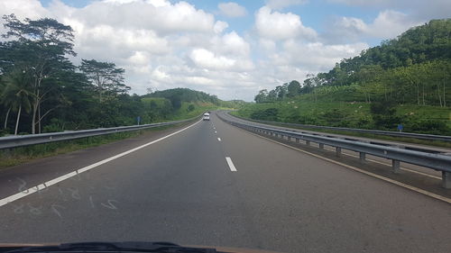 Road amidst trees against sky