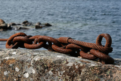 Close-up of rusty chain on retaining wall at harbor