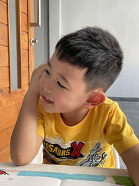 Portrait of cute boy sitting on table at home