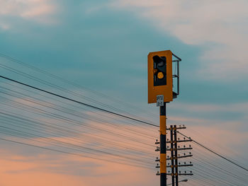 Low angle view of telephone pole against sky during sunset