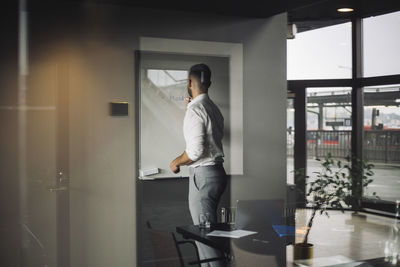 Side view of male it professional writing on white board in creative office