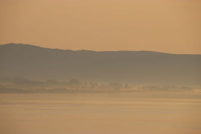 Scenic view of silhouette landscape against orange sky