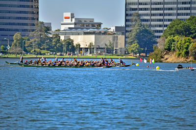 People rowing boat on river in city