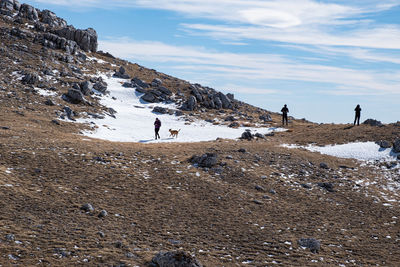 People on rocks against sky