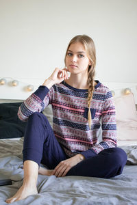 Portrait of young woman sitting on bed at home