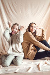 Sisters having fun on beige color textile background