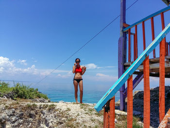 Young woman standing by sea against sky