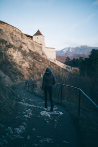 Rear view of man walking on built structure
