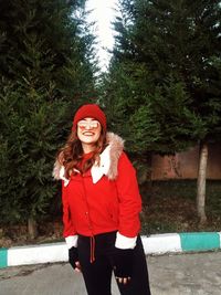 Portrait of smiling young woman standing against trees