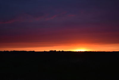 Scenic view of silhouette landscape against dramatic sky during sunset