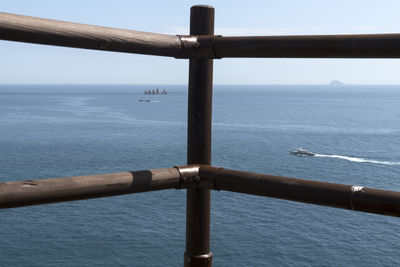 Close-up of railing by sea against sky