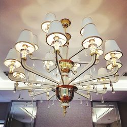 Low angle view of illuminated light bulb hanging on ceiling